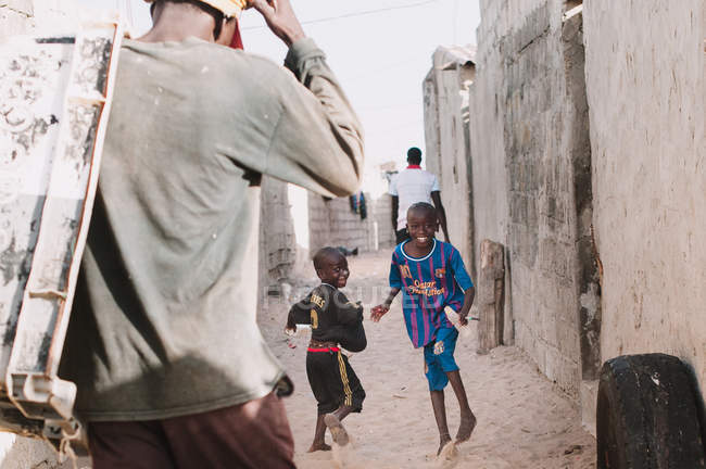Yoff, senegal- 6. Dezember 2017: lächelnde junge afrikanische Kinder, die Spaß haben und auf den Straßen des Dorfes spielen. — Stockfoto