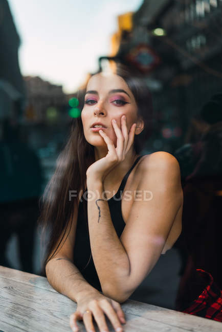 View through window to brunette girl looking at camera — Stock Photo