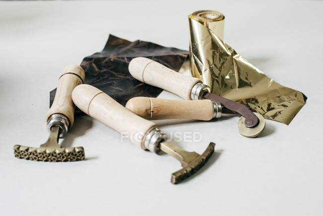 Pile of tools and gold roll for embossing stamps on leather. — Stock Photo