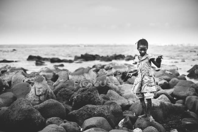 Yoff, Senegal- Dezembro 6, 2017: Retrato de menina de pé sobre pedras à beira-mar . — Fotografia de Stock