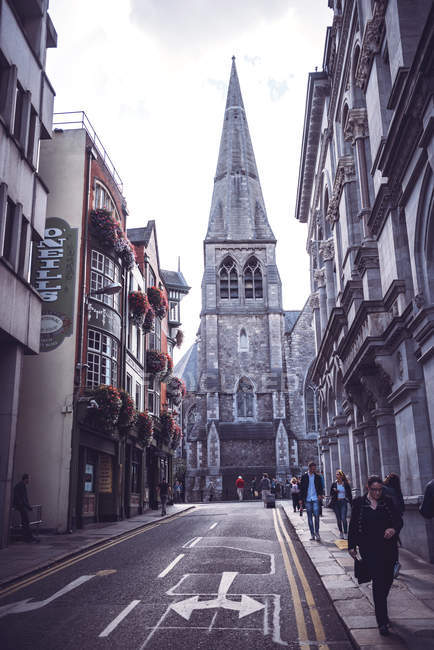 Vue en angle bas de l'ancien bâtiment cathédrale debout sur une rue étroite avec des piétons — Photo de stock