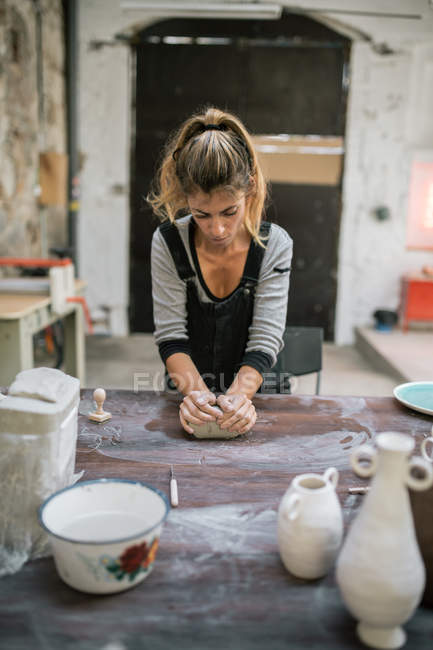Frontansicht des konzentrierten Töpfers beim Kneten von Ton auf dem Tisch in der Werkstatt — Stockfoto
