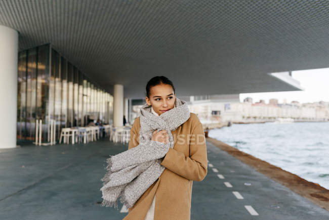 Portrait of dreamy girl wrapping in coat and walking near water — Stock Photo