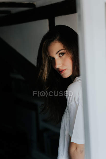 Sensual brunette girl in t-shirt looking over shoulder at camera — Stock Photo