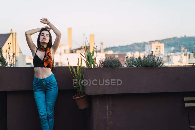 Brunette girl posing on balcony with arms raised and eyes closed — Stock Photo