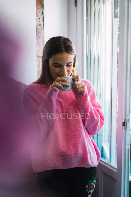 Ritratto di donna in felpa rosa che prende un caffè a casa — Foto stock