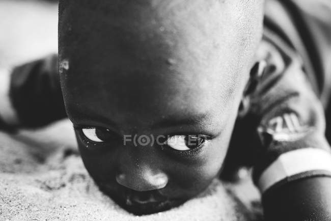 Goree, Senegal- 6 dicembre 2017: Ritratto ravvicinato di un ragazzo sdraiato sulla sabbia e disteso a guardare — Foto stock