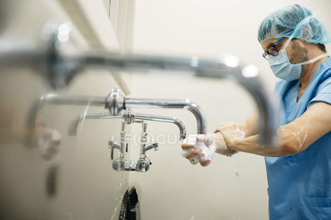 Боковой вид вдумчивого хирурга, моющего руки перед операцией — стоковое фото