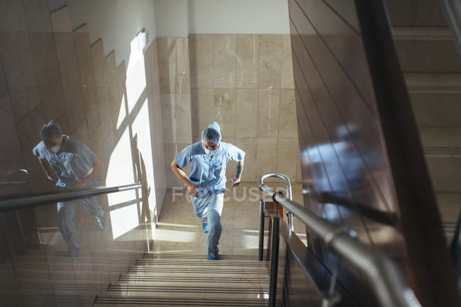 Vista basso angolo di uomo in uniforme correre su per le scale in ospedale — Foto stock