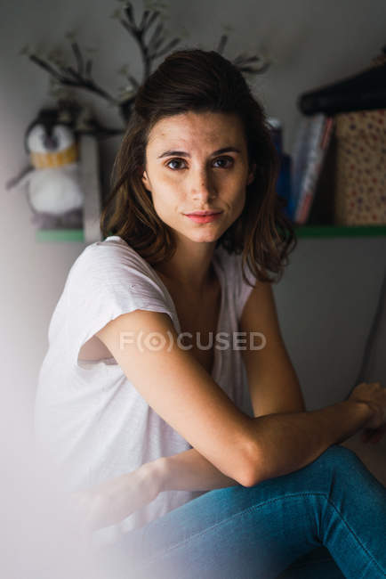 Brunette woman sitting on bed and looking at camera — Stock Photo