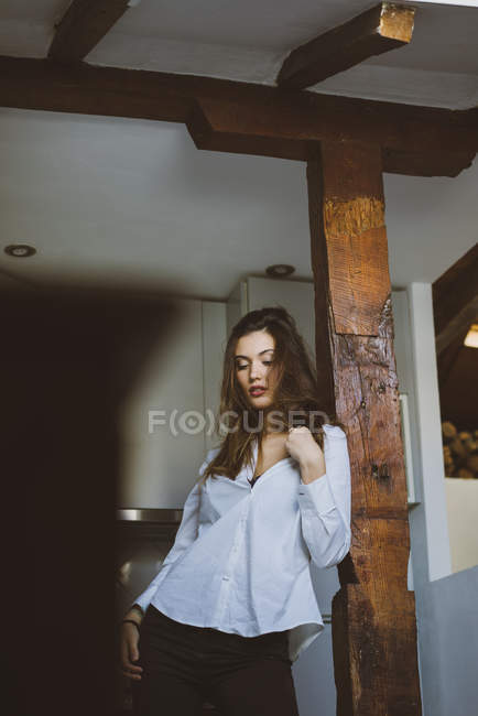 Спокуслива брюнетка дівчина позує на дерев'яному пілоні вдома — стокове фото