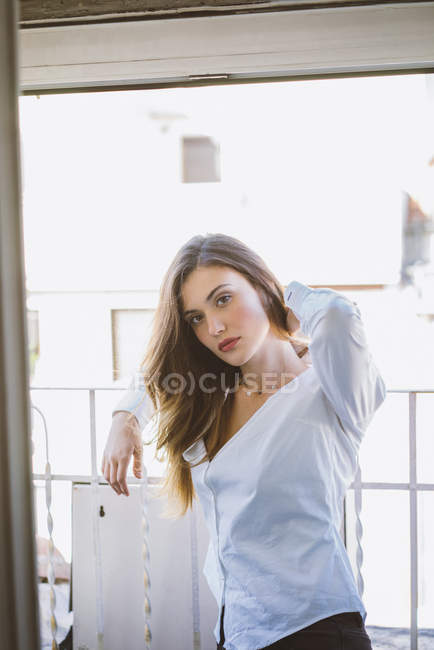 Chica morena sensual posando en balcón detrás de cristal de la ventana - foto de stock
