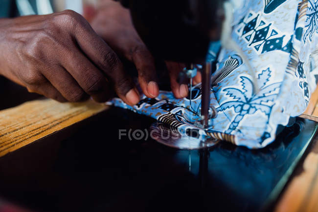 Обрізати руки шити одяг зі світло-блакитної тканини на старій швейній машині . — стокове фото
