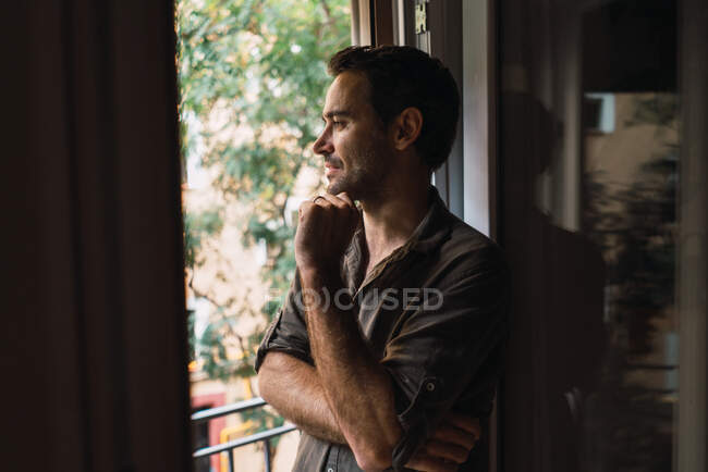 Homem de conteúdo pensativo olhando pela janela — Fotografia de Stock