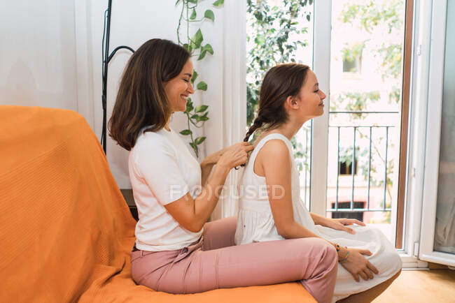 Content woman braiding charming daughter — Stock Photo