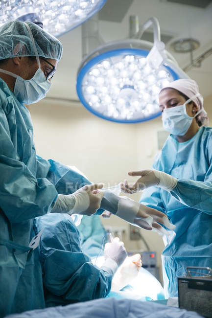 Vista lateral do curativo da equipe médica na sala de cirurgia antes da operação — Fotografia de Stock
