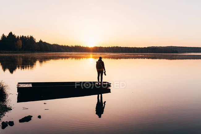 Silhouette eines Mannes, der im Morgennebel auf einem Boot am Seeufer steht — Stockfoto