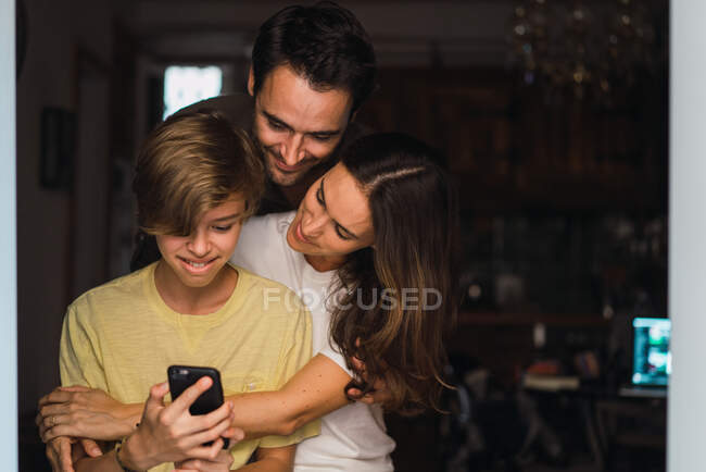 Los padres contentos con el hijo viendo teléfono - foto de stock