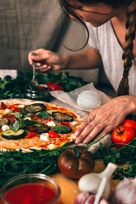Casual woman pouring pizza with delicious sauce while cooking. — Stock Photo