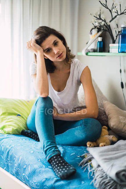 Brünettes Mädchen posiert auf dem Bett und schaut in die Kamera — Stockfoto