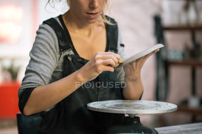 Mid section of female potter carving clay dish — Stock Photo