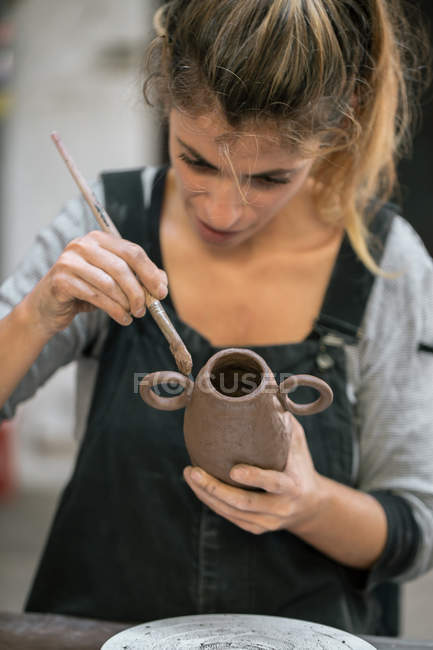 Вид спереду жінки скляний глиняний горщик з пензлем — стокове фото