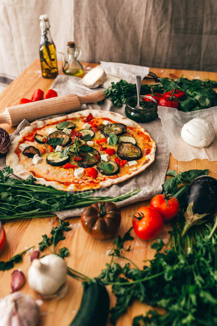 Vista de ángulo bajo de pizza e ingredientes en mesa de madera - foto de stock