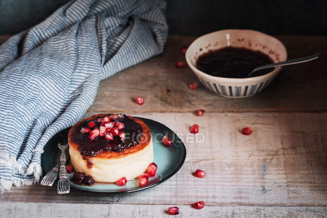 Cheesecake with berries jam and pomegranate in rustic plate — Stock Photo