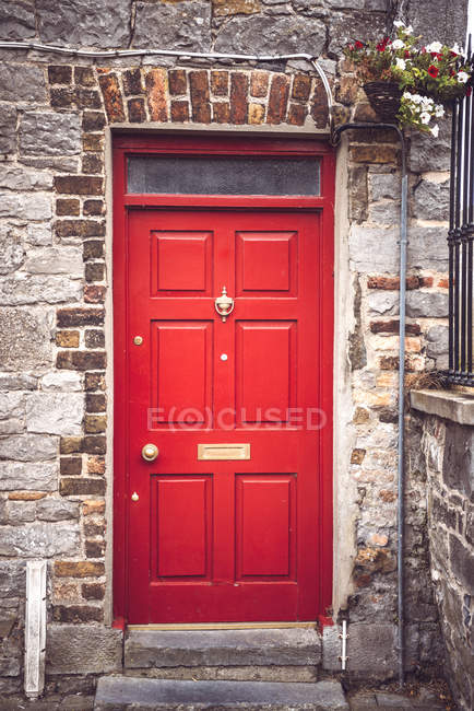 Bright red door in brick wall of common rural  house. — Stock Photo