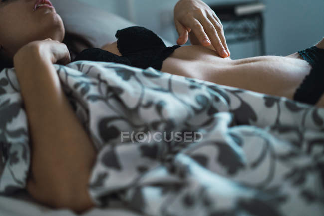 Crop bruna donna in reggiseno dormire a letto a casa — Foto stock