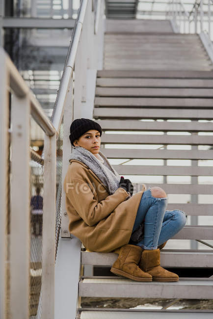 Vista lateral da mulher posando na escada e olhando para a câmera — Fotografia de Stock