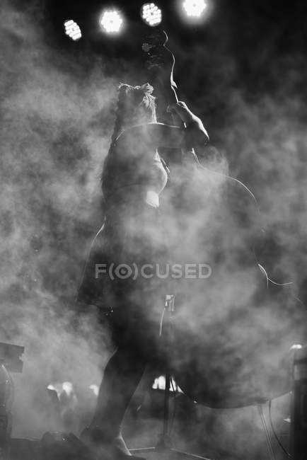 Rear view of female cellist playing on stage  with fog — Stock Photo