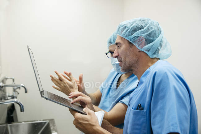 Side view of surgeon showing laptop to colleague — Stock Photo