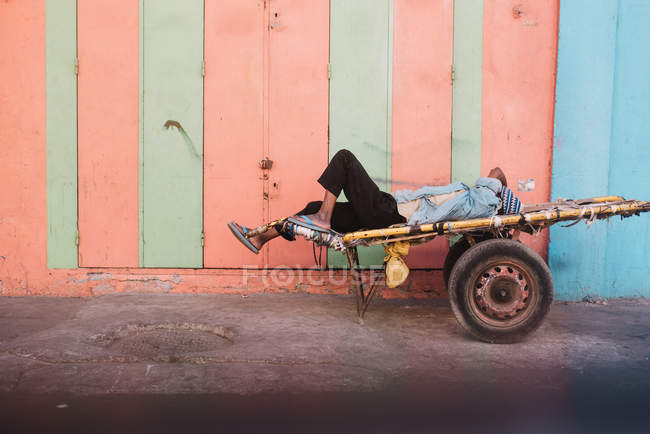 Seitenansicht eines schlafenden Mannes auf einem Wagen an einer bunten Wand. — Stockfoto