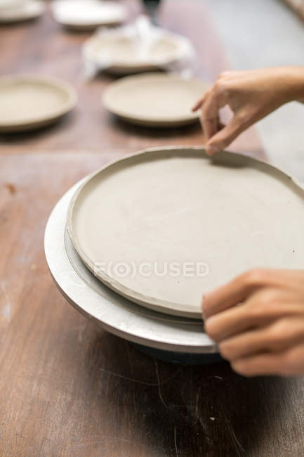 Crop female hands modeling plate with clay — Stock Photo