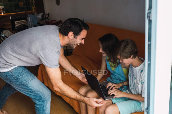 Pai e filhos usando o laptop — Fotografia de Stock
