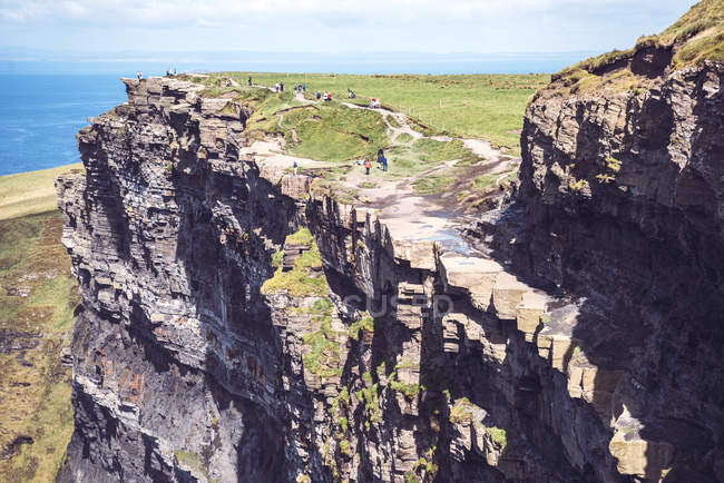 People walking on Moher cliffs on sunny day — Stock Photo