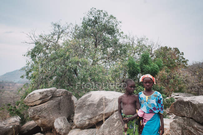 Yoff, Sénégal- 6 décembre 2017 : Des enfants sérieux en vêtements brillants posant contre les rochers et le paysage naturel . — Photo de stock