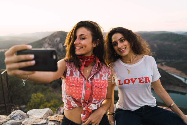 Two smiling women taking selfie over breathtaking landscape — Stock Photo