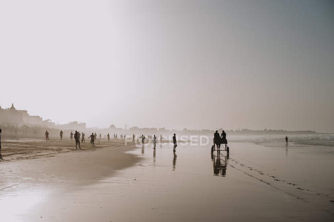 Yoff, Senegal- 6 dicembre 2017: Veduta della spiaggia nella foschia con le persone che passano il tempo — Foto stock