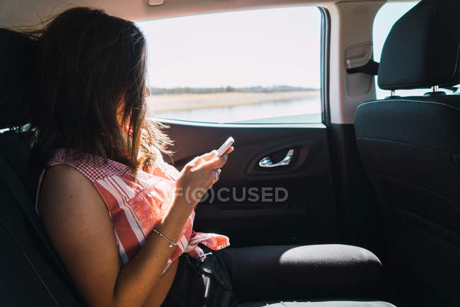 Vue latérale du téléphone de navigation femme brune en voiture — Photo de stock