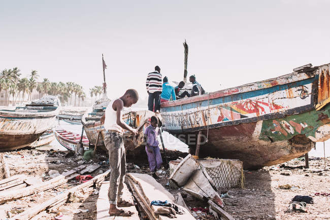 Goree, Senegal- December 6, 2017: African children playing near old damaged boat on sunny day. — Stock Photo