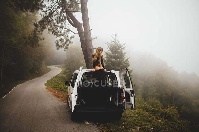 Woman sitting on top of car — Stock Photo