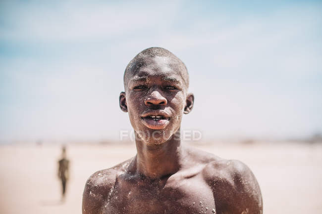 Yoff, senegal- 6. Dezember 2017: Porträt eines mit Sand bedeckten Mannes, der in der Wüste steht und in die Kamera blickt. — Stockfoto