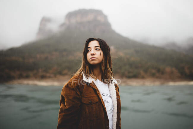 Hübsche junge Frau steht in der Nähe des Flusses auf einem Hügel. — Stockfoto