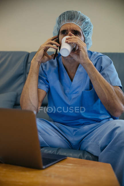 Portrait of doctor drinking coffee and talki — Stock Photo