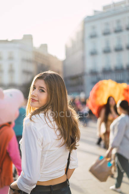 Brunette girl looking over shoulder at camera at street scene — Stock Photo