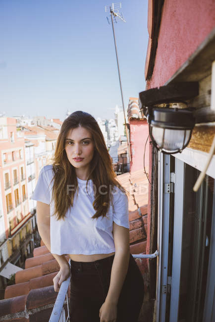 Bruna ragazza appoggiata sul balcone corrimano e guardando la fotocamera — Foto stock