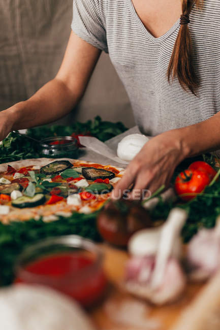 Mujer de la cosecha preparando pizza en la mesa de la cocina - foto de stock