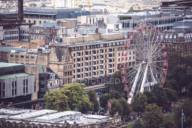 Vista de ângulo alto da roda gigante entre fachadas de edifícios de cidade — Fotografia de Stock